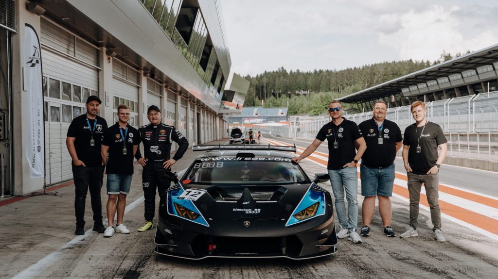 Rennteam vor Sportwagen posing